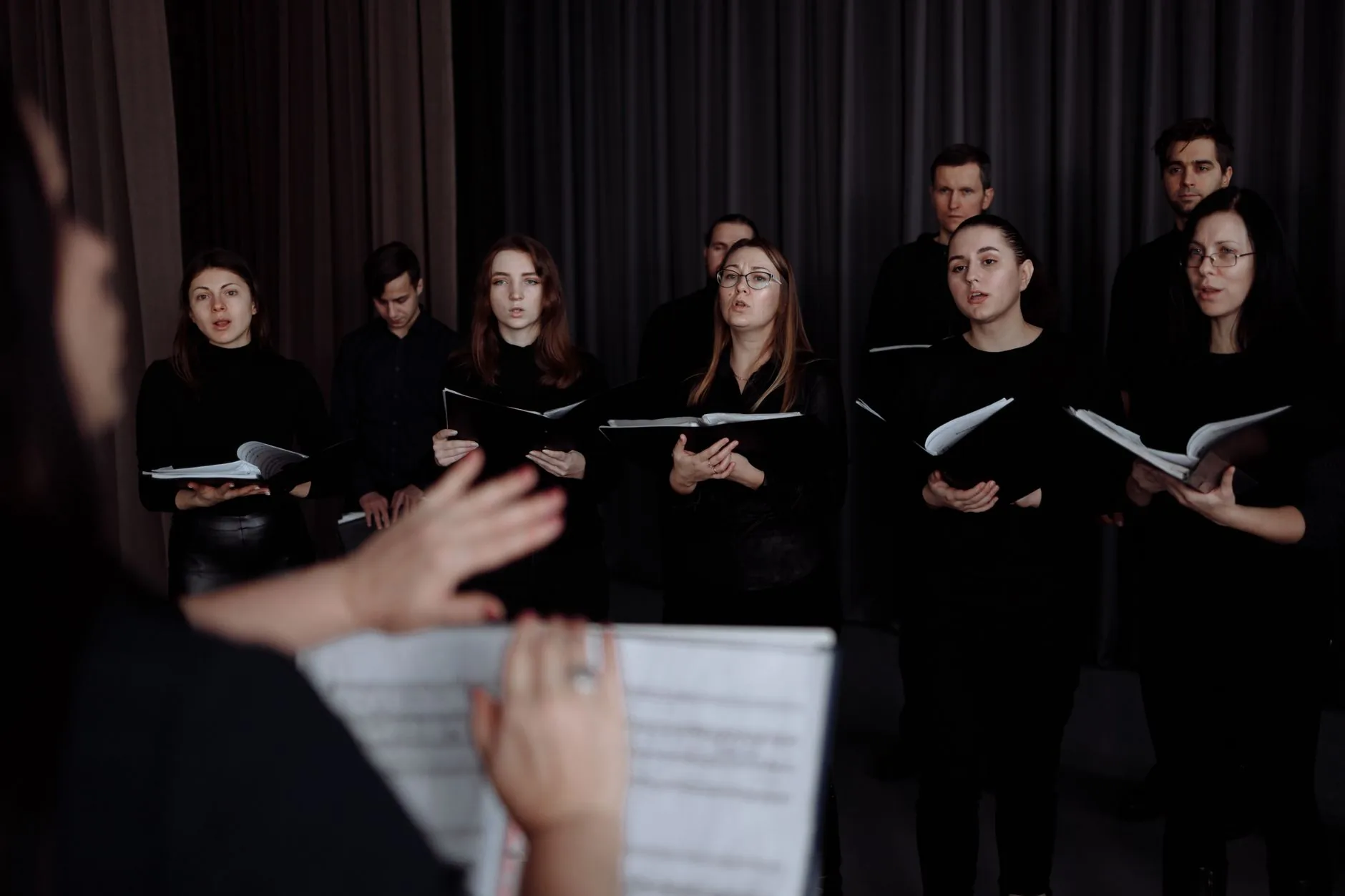 Greg Beardsell conducting a choir, muted colors, soft lighting, ordinary photograph style.