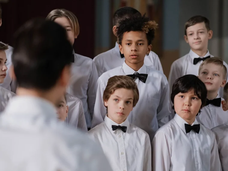 Young girl in navy choir robe, smiling, youth choir group in background.