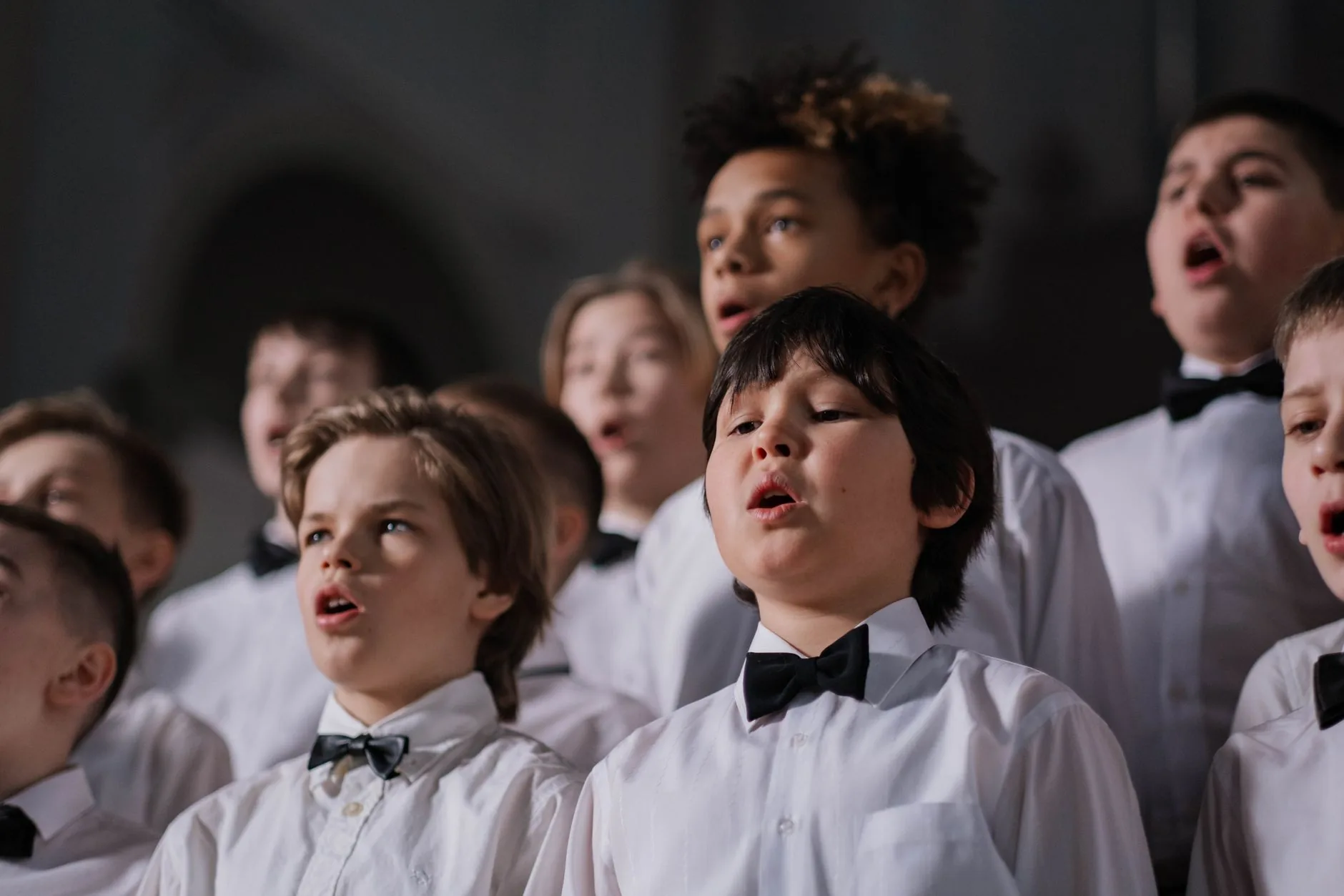 Girl singing, surrounded by other young singers, choral rehearsal, treble voices.